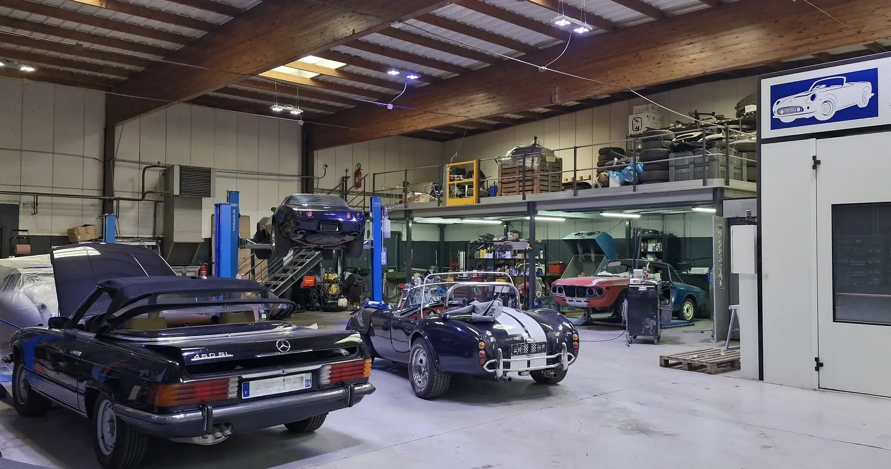 Intérieur de l'atelier Retro Mecanic : Mercedes 450 SL, réplique de Cobra, ponts élévateurs et mezzanine de stockage