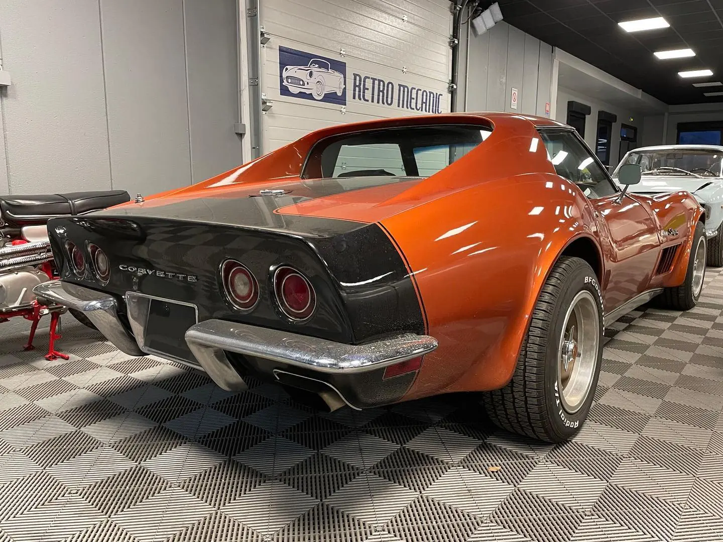 Chevrolet Corvette Stingray orange et noire, vue arrière, dans le hall Retro Mecanic
