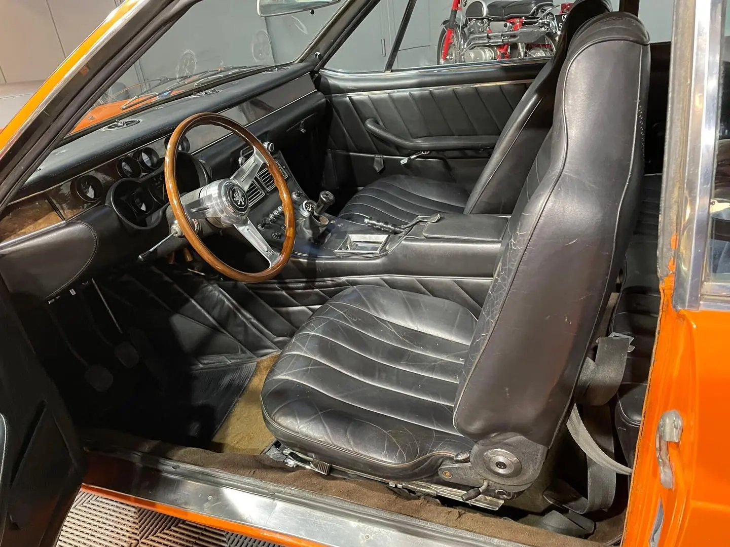 Habitacle d'un coupé Iso Rivolta : sièges en cuir noir, volant bois et planche de bord