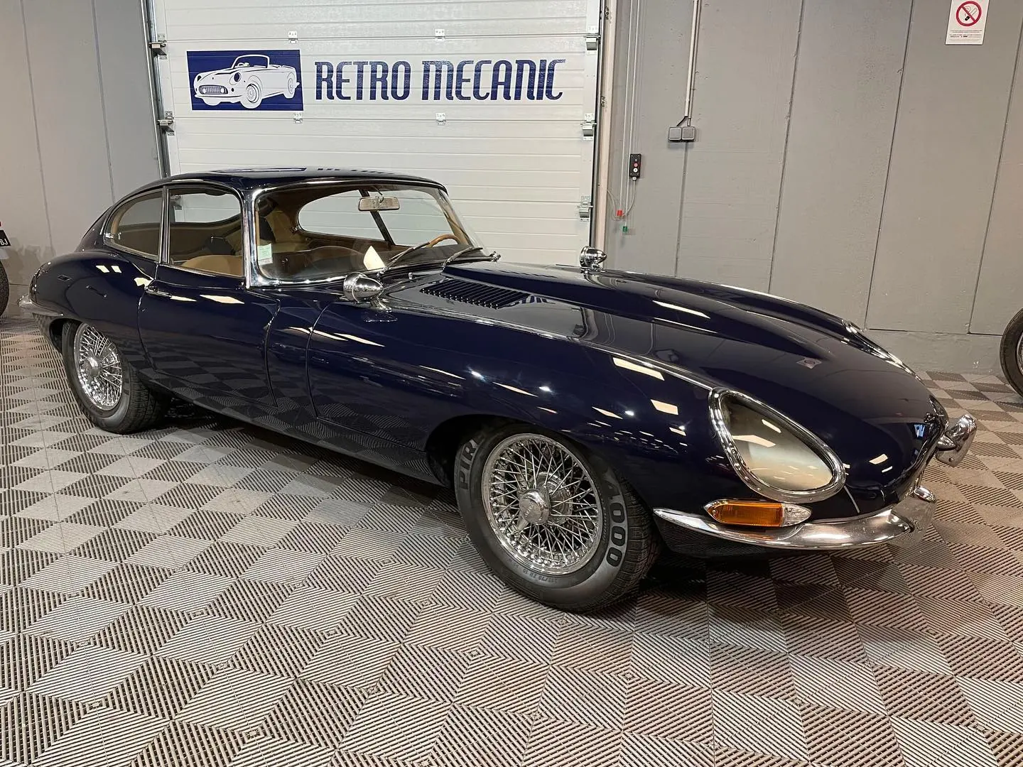 Jaguar Type E coupé bleu nuit à roues à rayons, dans le hall Retro Mecanic