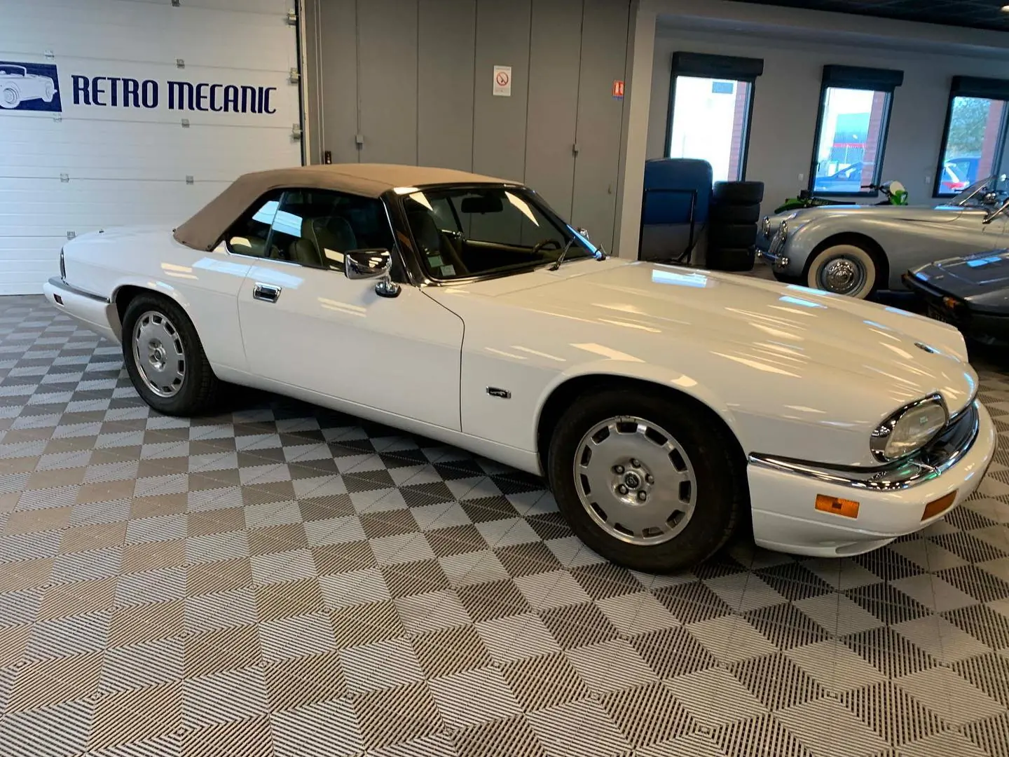Jaguar XJS cabriolet blanc à capote beige, dans le hall Retro Mecanic