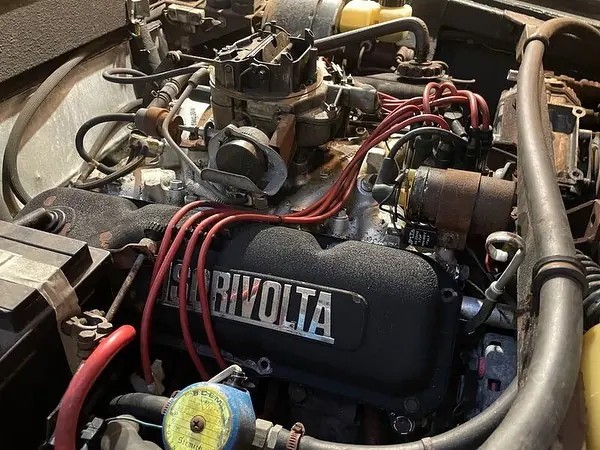 Moteur V8 d'une Iso Rivolta : cache-culbuteurs noir, fils de bougie rouges et carburateur