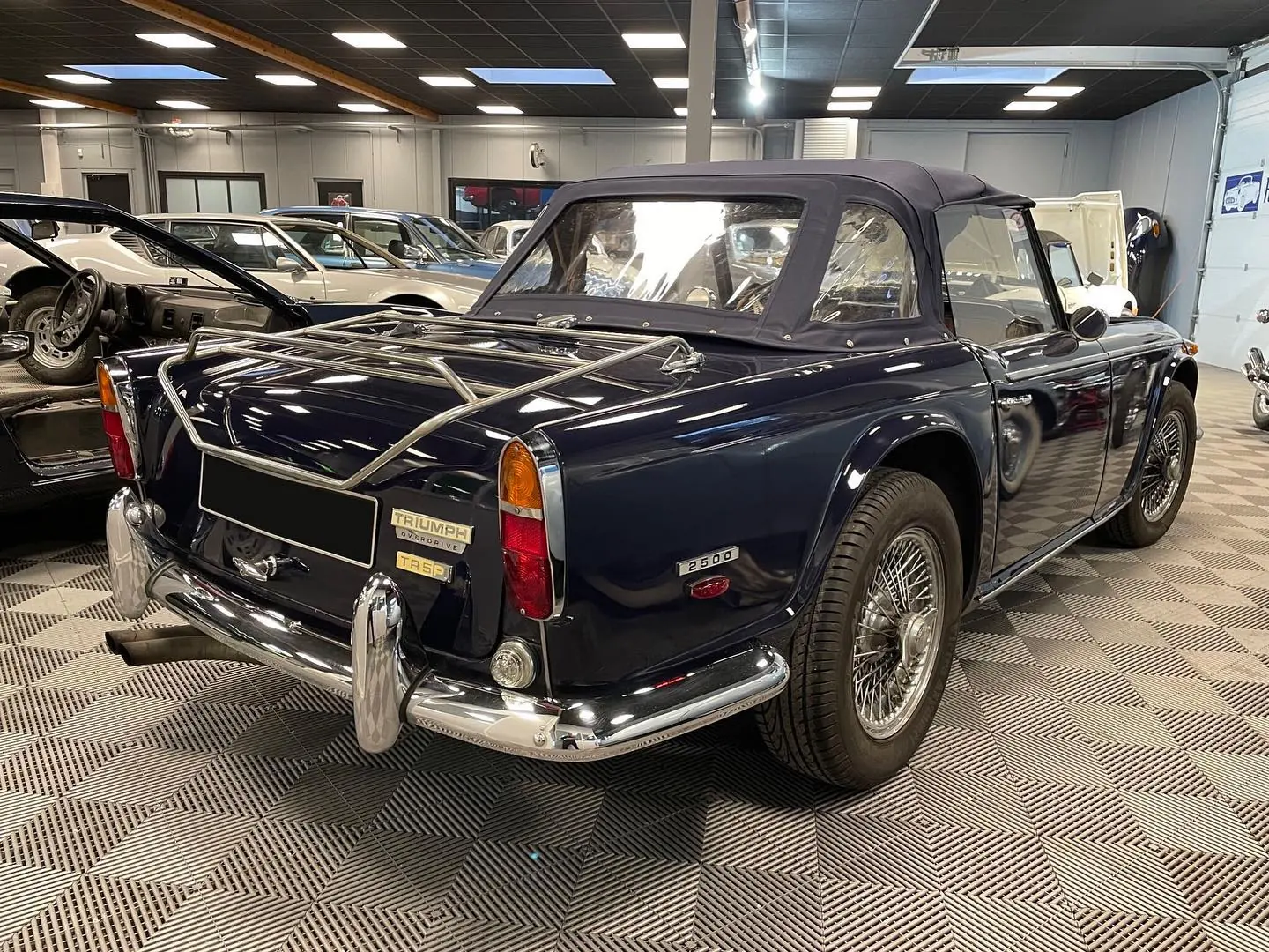 Triumph TR5 bleu nuit, capote et porte-bagages chromé, dans le hall Retro Mecanic