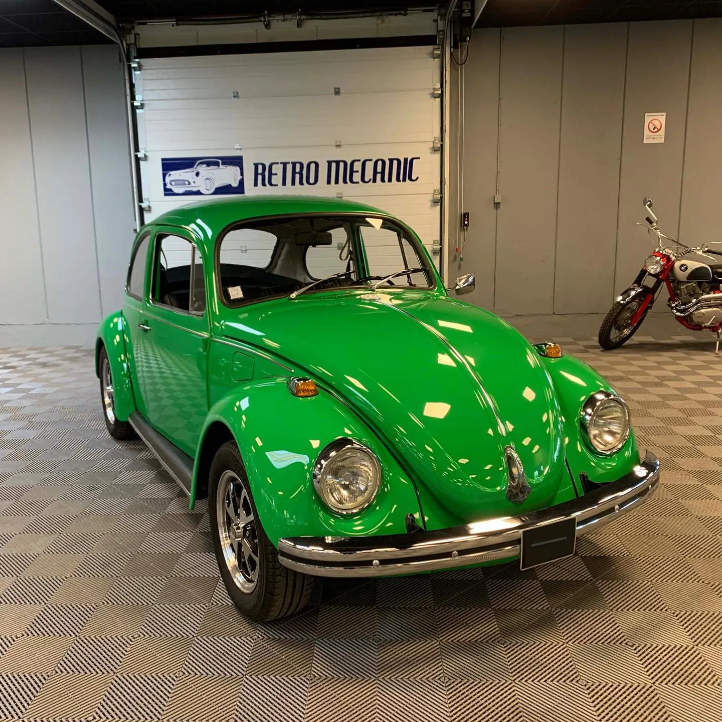 Volkswagen Coccinelle verte restaurée, devant le logo Retro Mecanic